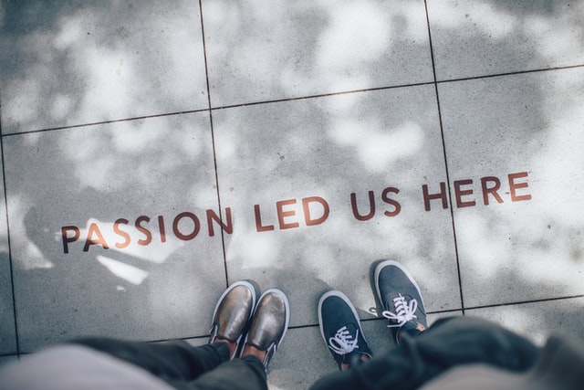 two people looking down at a sidewalk with the words “passion led us here” painted on it.