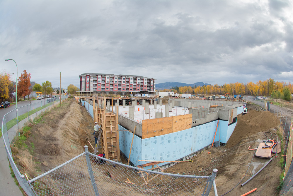 Construction of condominium building with a newly build building behind the construction site.