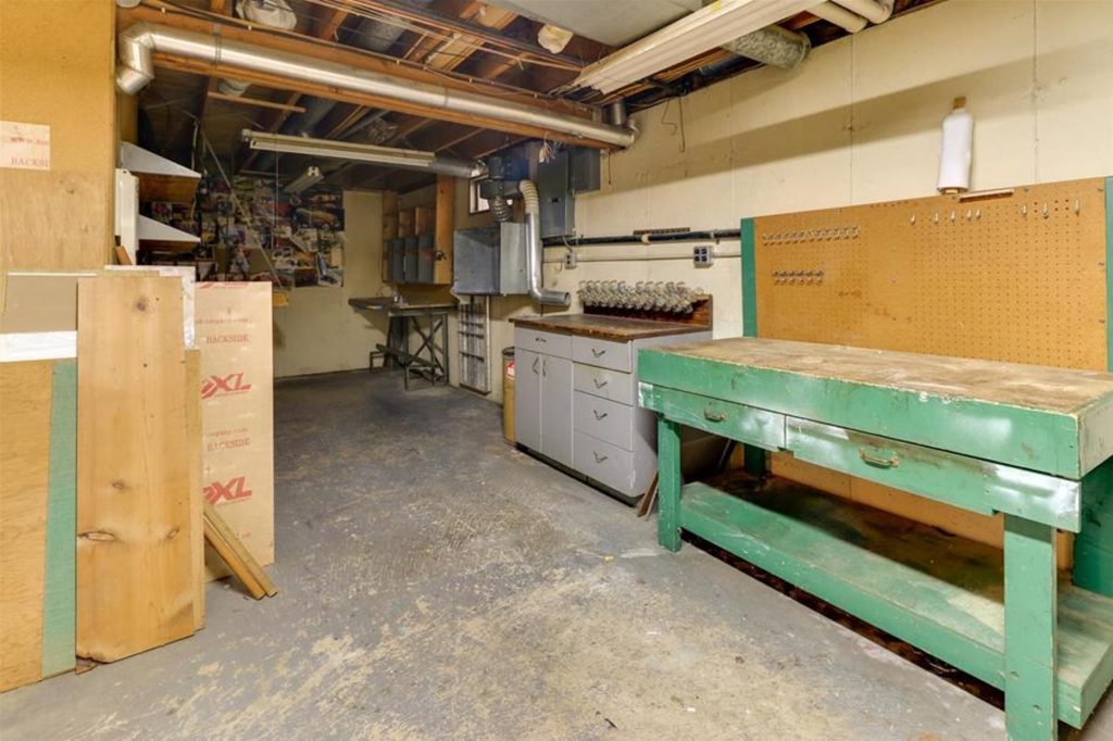 Basement workshop. Showing a green wooden workbench, cabinets, and work table.