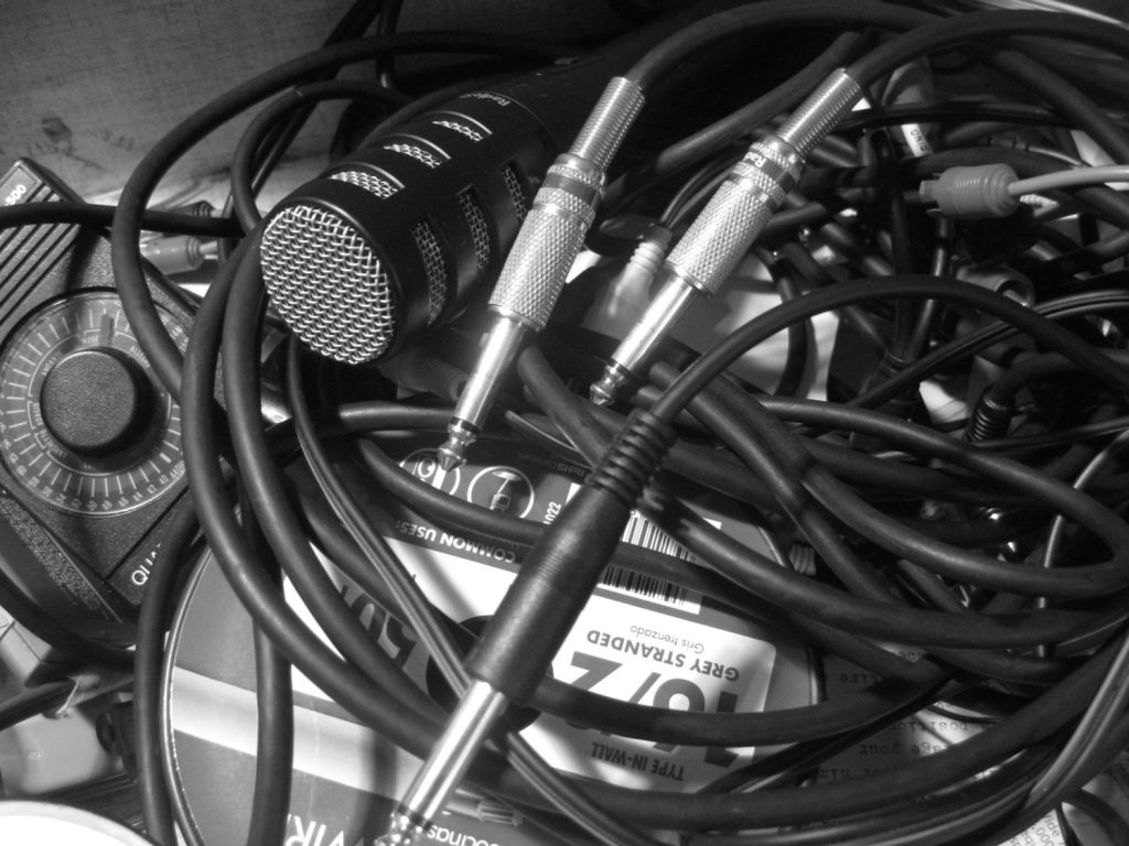 A tangled nest of audio cables. A microphone protrudes from the tangle.