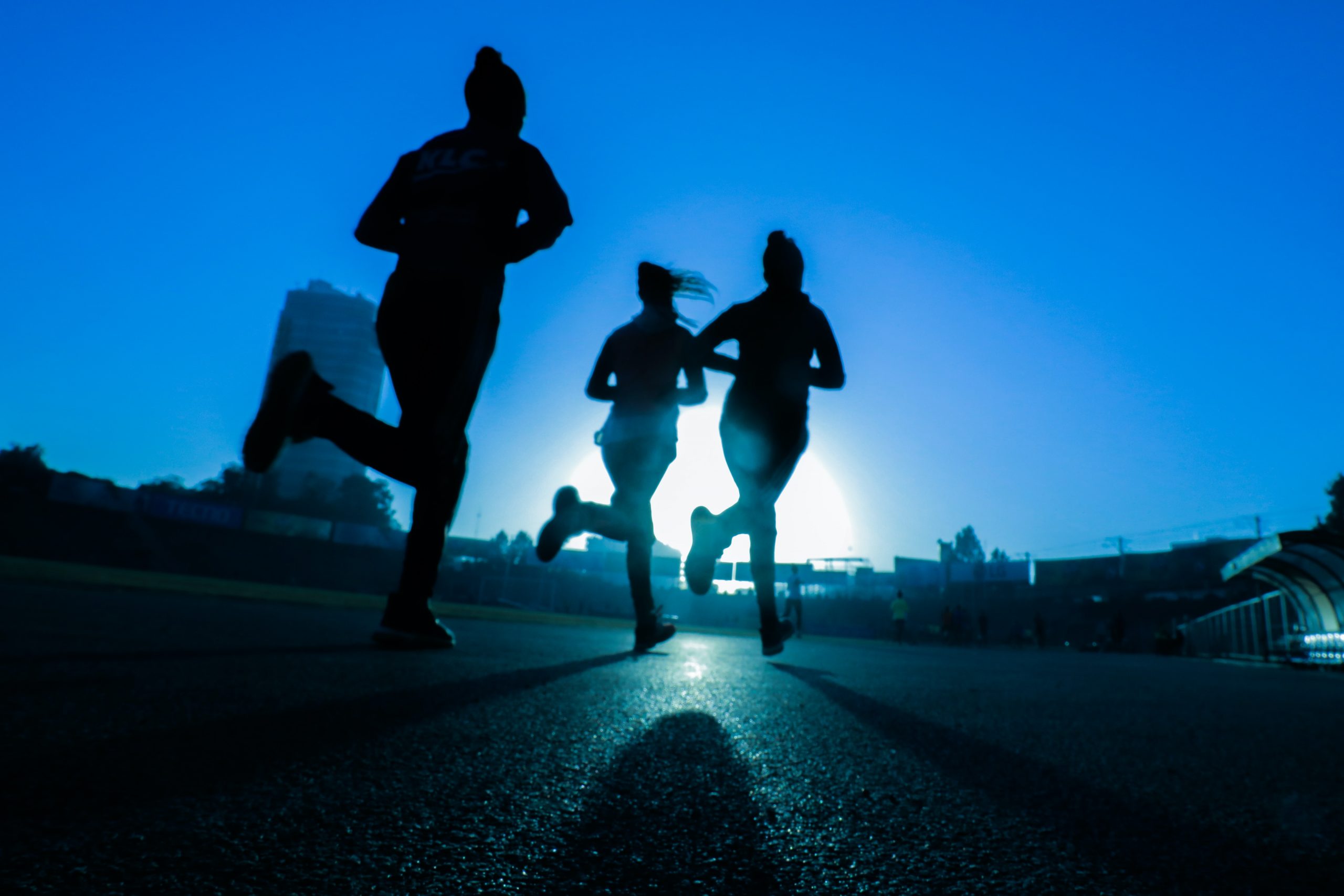 Silhouettes of three runners on a city street